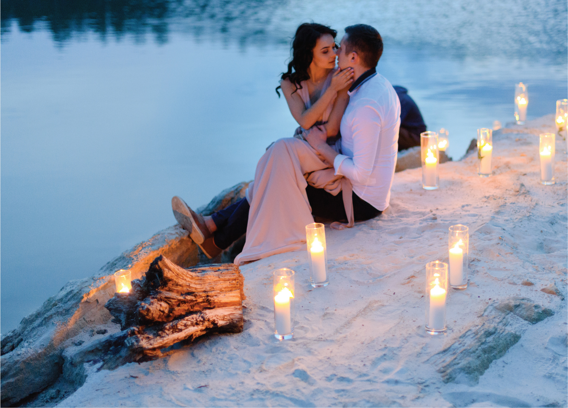 Couple embracing on a candlelit beach at dusk
