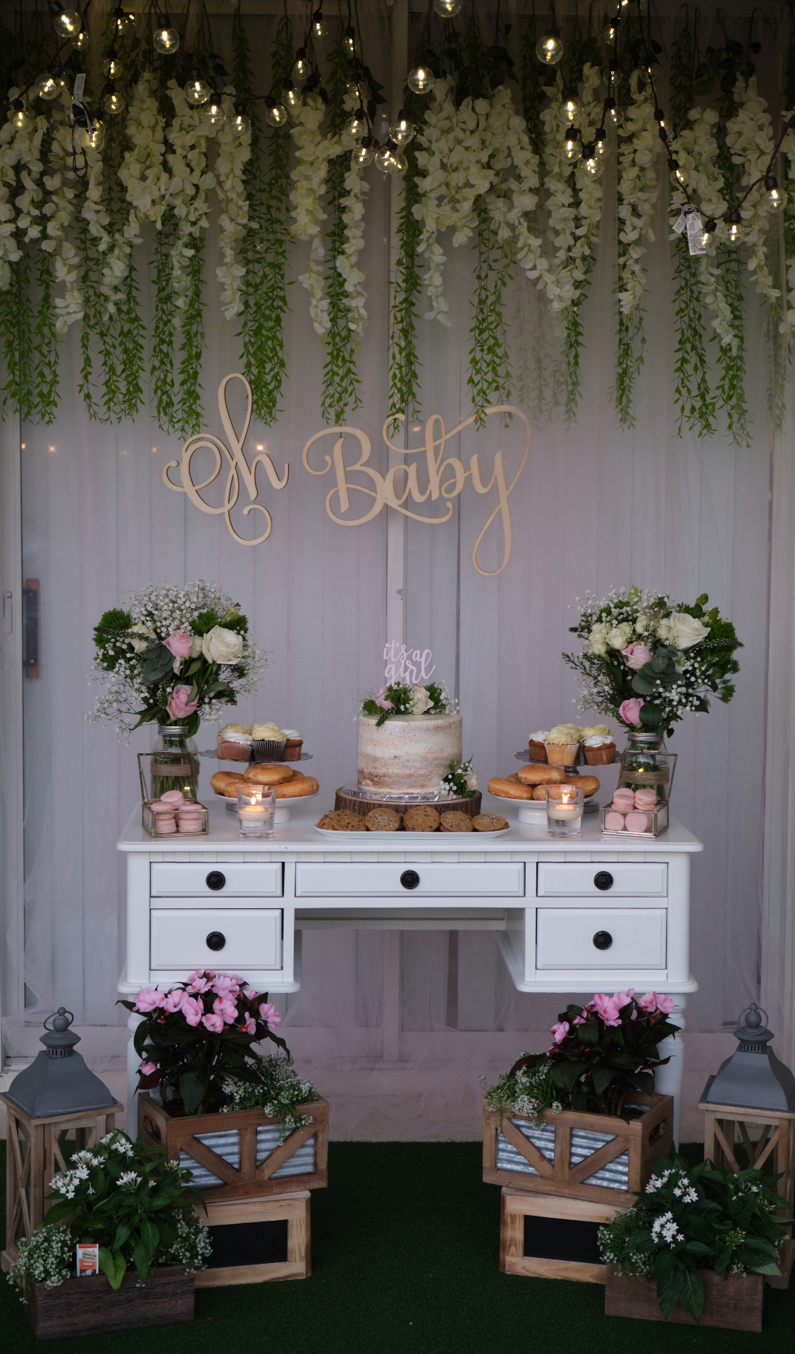 Baby shower dessert table with floral arrangements, cake and sweet treats