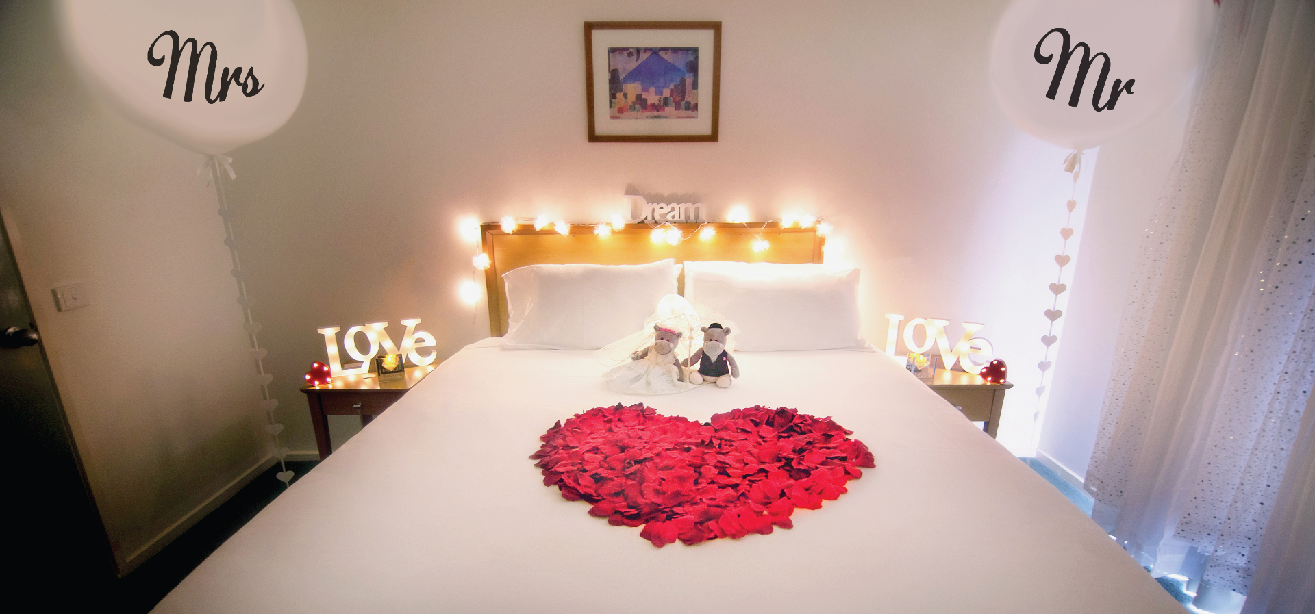 Honeymoon suite styled with Mr & Mrs balloons, rose petal heart and fairy lights
